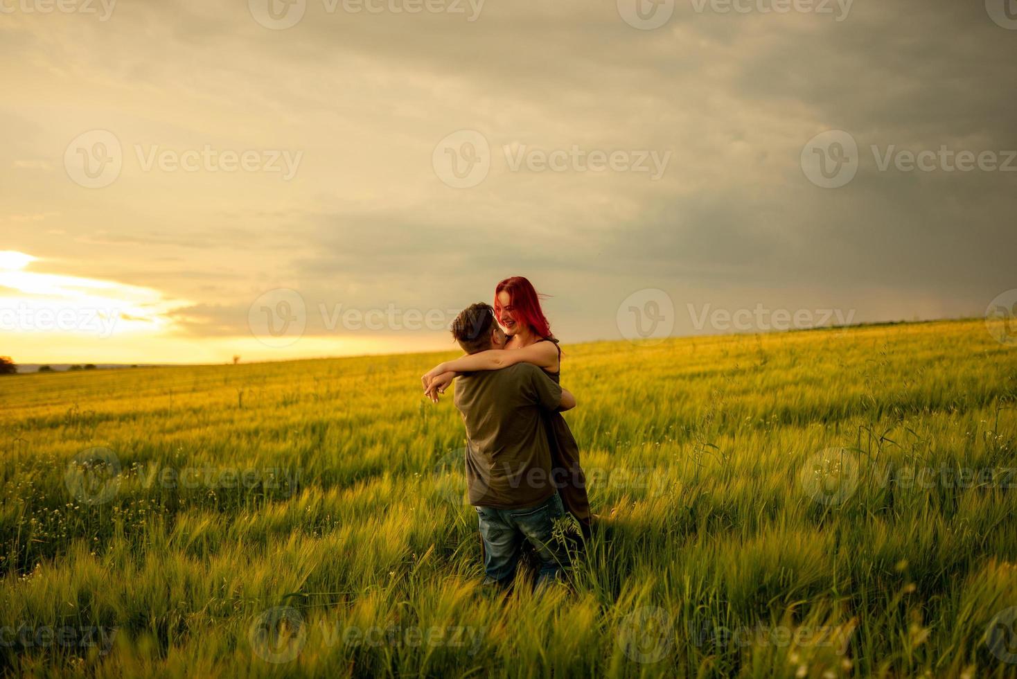 um homem e uma mulher estão deitados de costas em um campo de trigo. um homem beija uma mulher na bochecha. a garota abriu a boca com prazer. foto