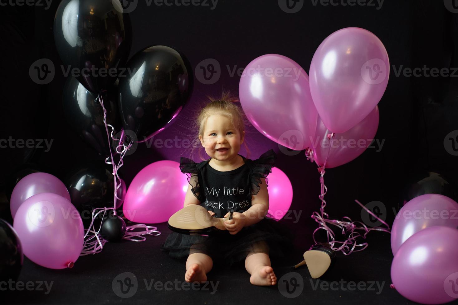 dia da festa de aniversário da menina do primeiro ano. balões e férias dentro de casa. aniversário da criança. menina bonita em seu primeiro vestido preto foto