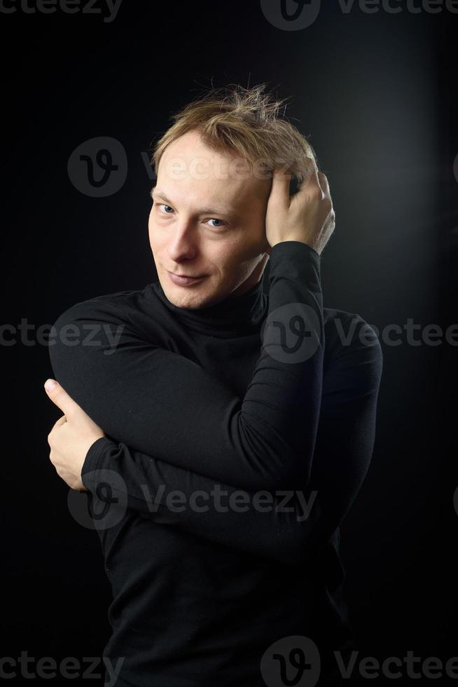 retrato de determinado homem bonito vestindo camisa preta, fundo preto. foto