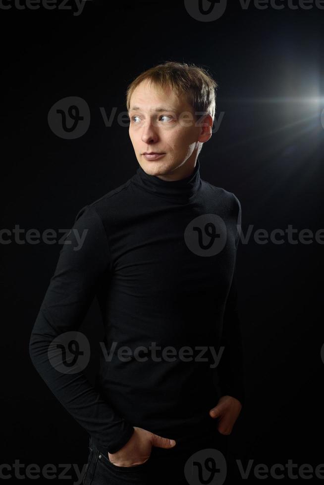 retrato de determinado homem bonito vestindo camisa preta, fundo preto. foto