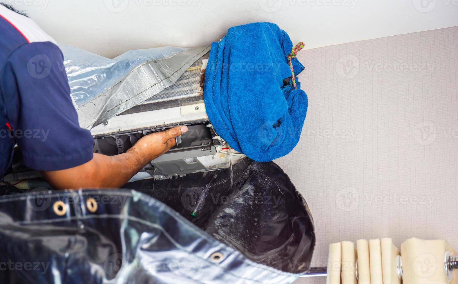 close-up de reparo de ar condicionado, reparador verificando e limpando um sistema de ar condicionado de sala foto