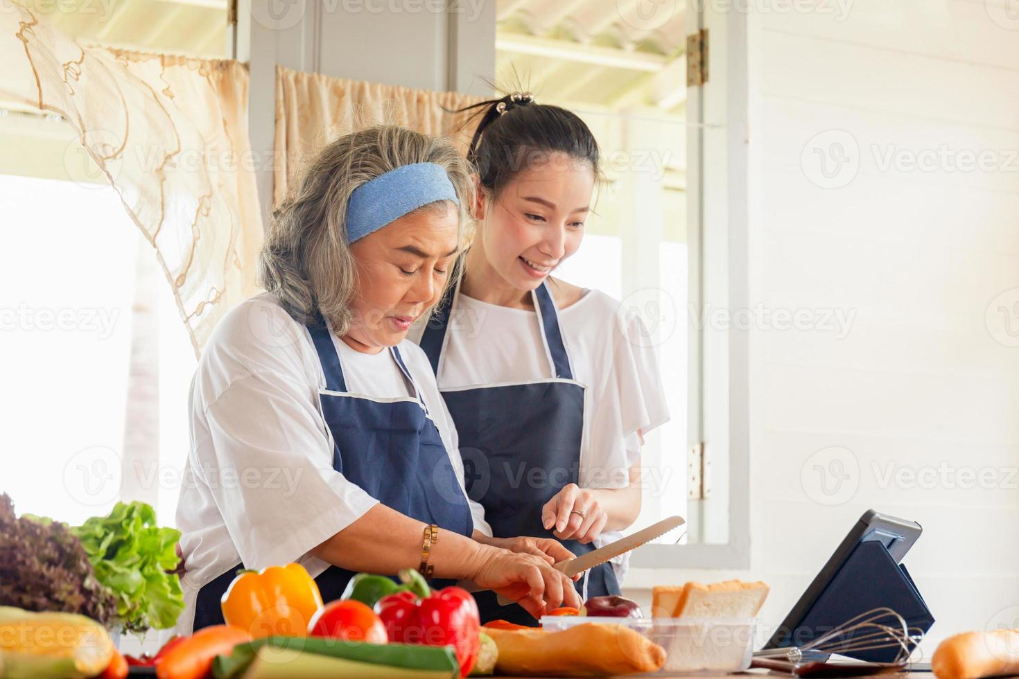 mãe asiática sênior e filha de meia idade cozinhando juntos na cozinha foto