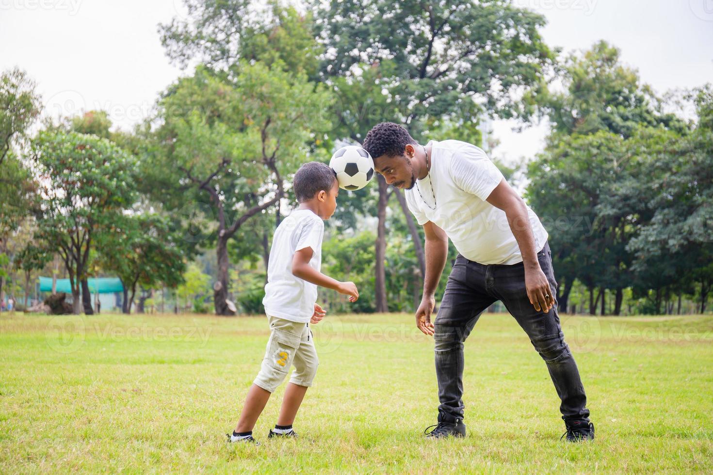 alegre pai e filho afro-americano jogando futebol no parque, conceitos de família de felicidade foto