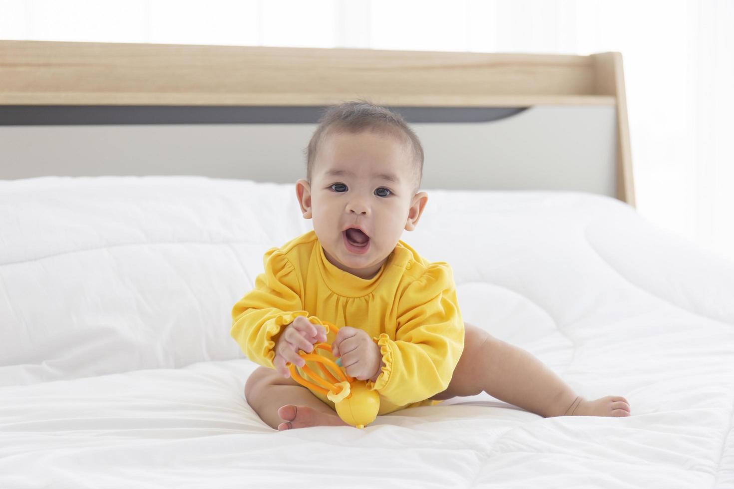 bebês asiáticos estão jogando brinquedos de bebê na cama. foto