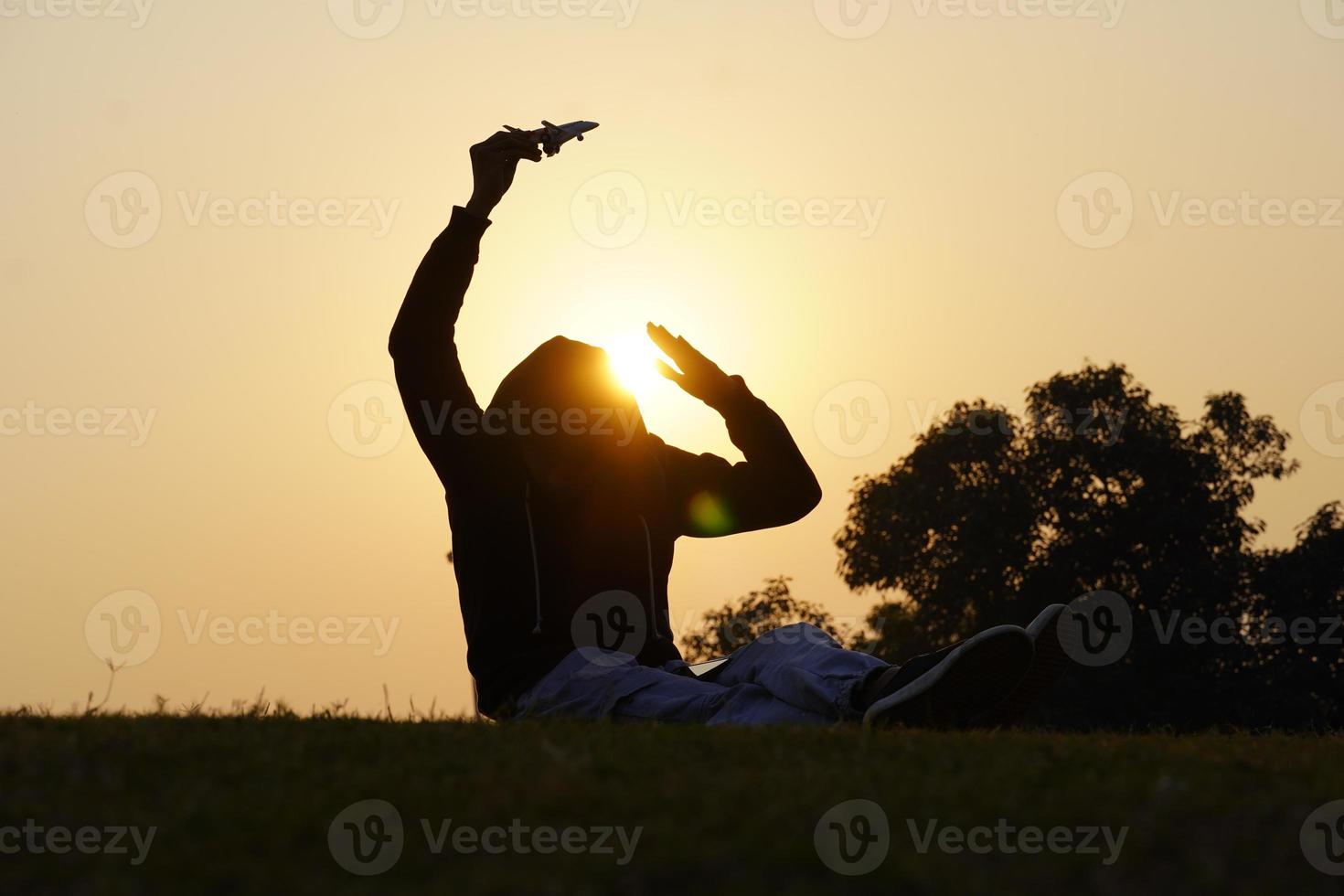 menino feliz com um avião de brinquedo em um fundo por do sol sobre um campo de trigo foto