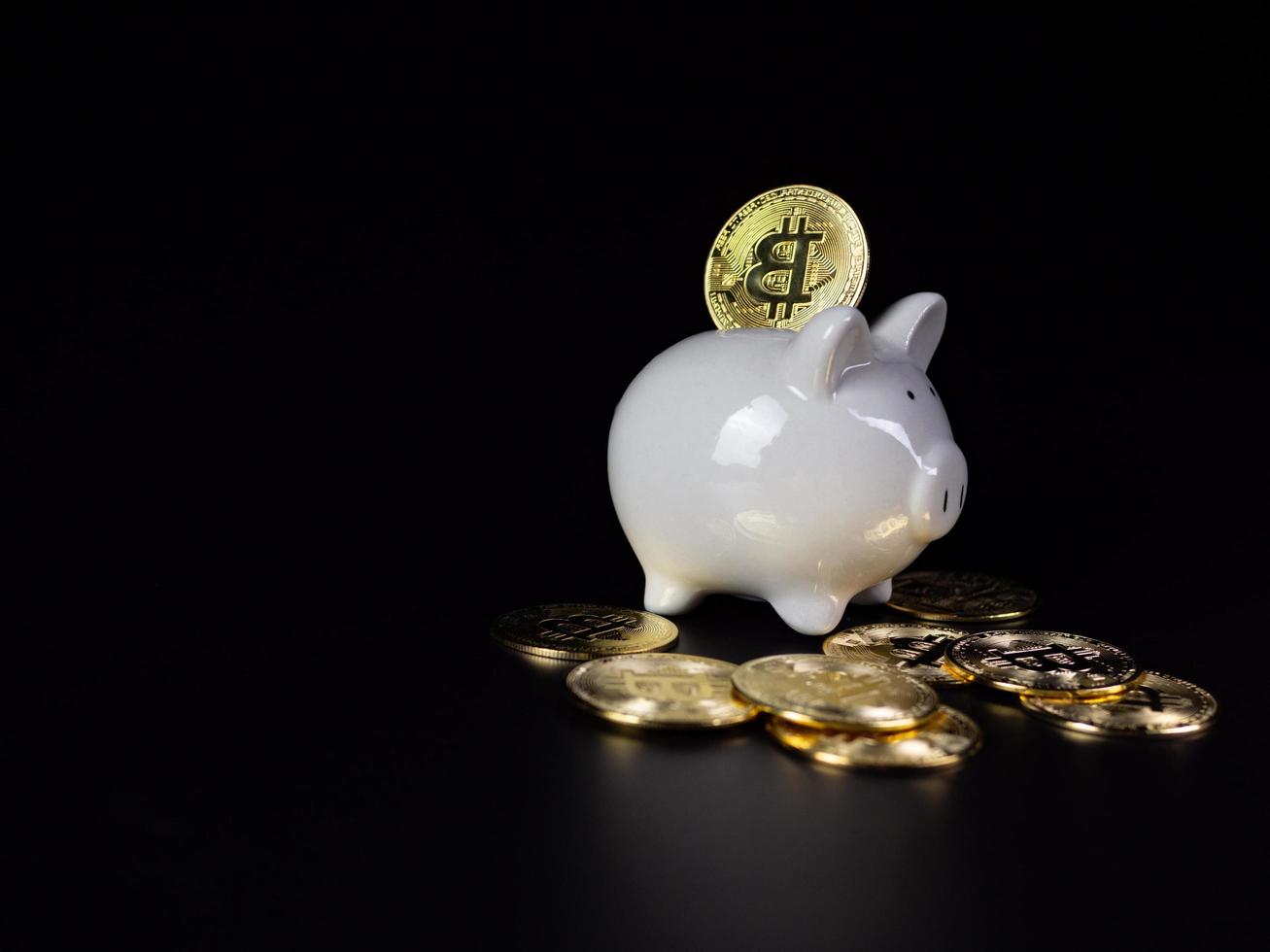 moedas de bitcoin estão na parte de trás de um cofrinho branco. em um fundo preto foto