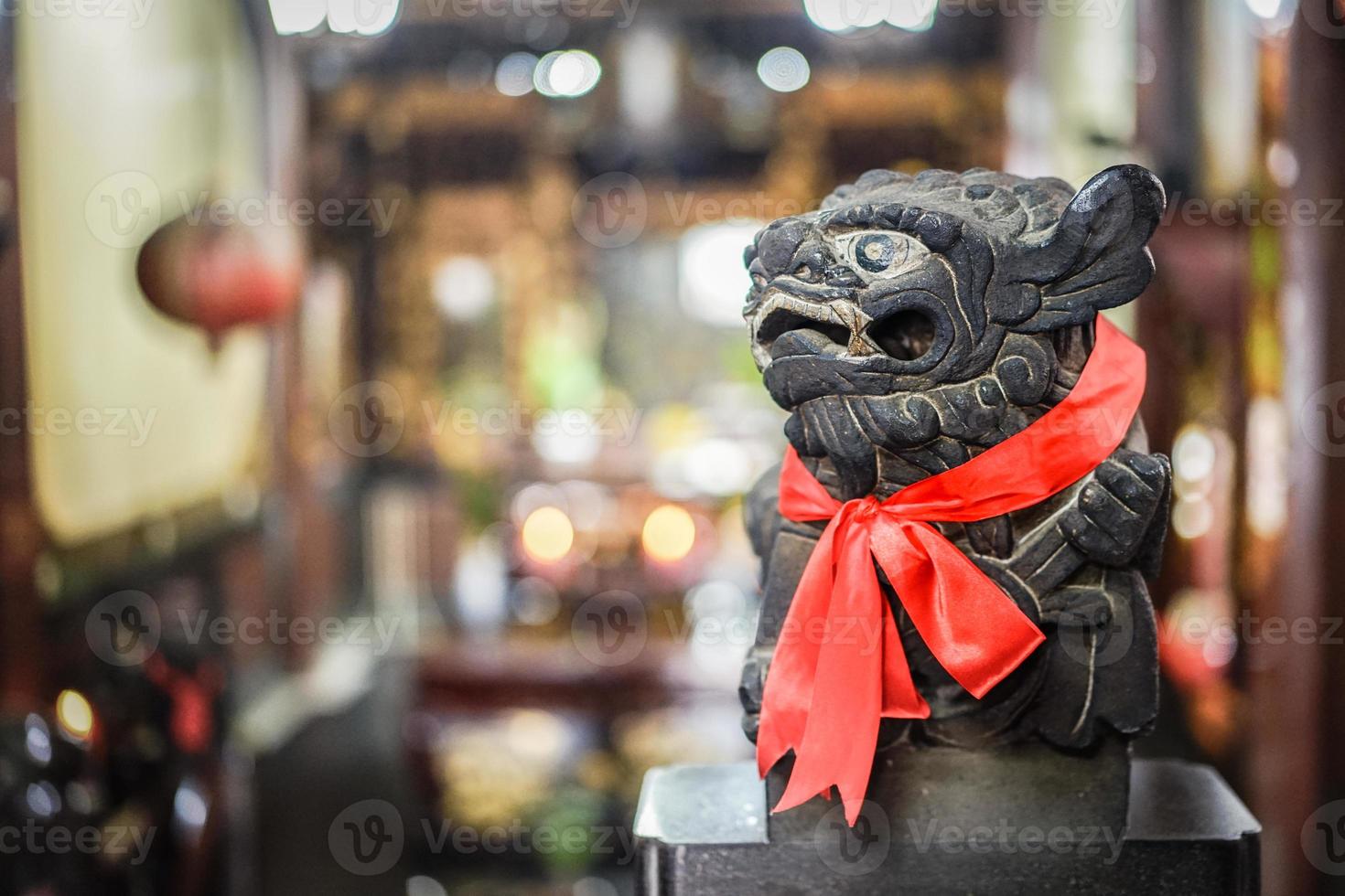 estátua de leão de pedra preta inteligente olha para o lado direito, lenço vermelho e fundo desfocado foto