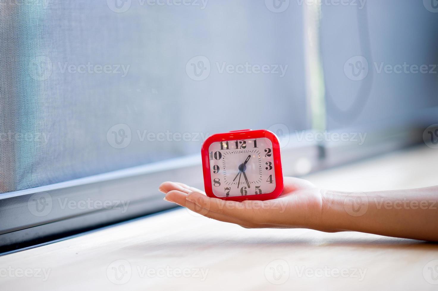 mão e despertador vermelho que mostra o alarme todas as manhãs, o conceito de pontualidade foto