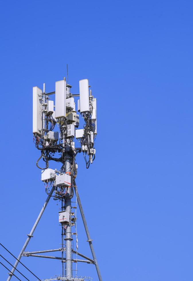 torre de telecomunicações com antena e equipamento para sistema de comunicação celular contra céu azul claro em quadro vertical foto