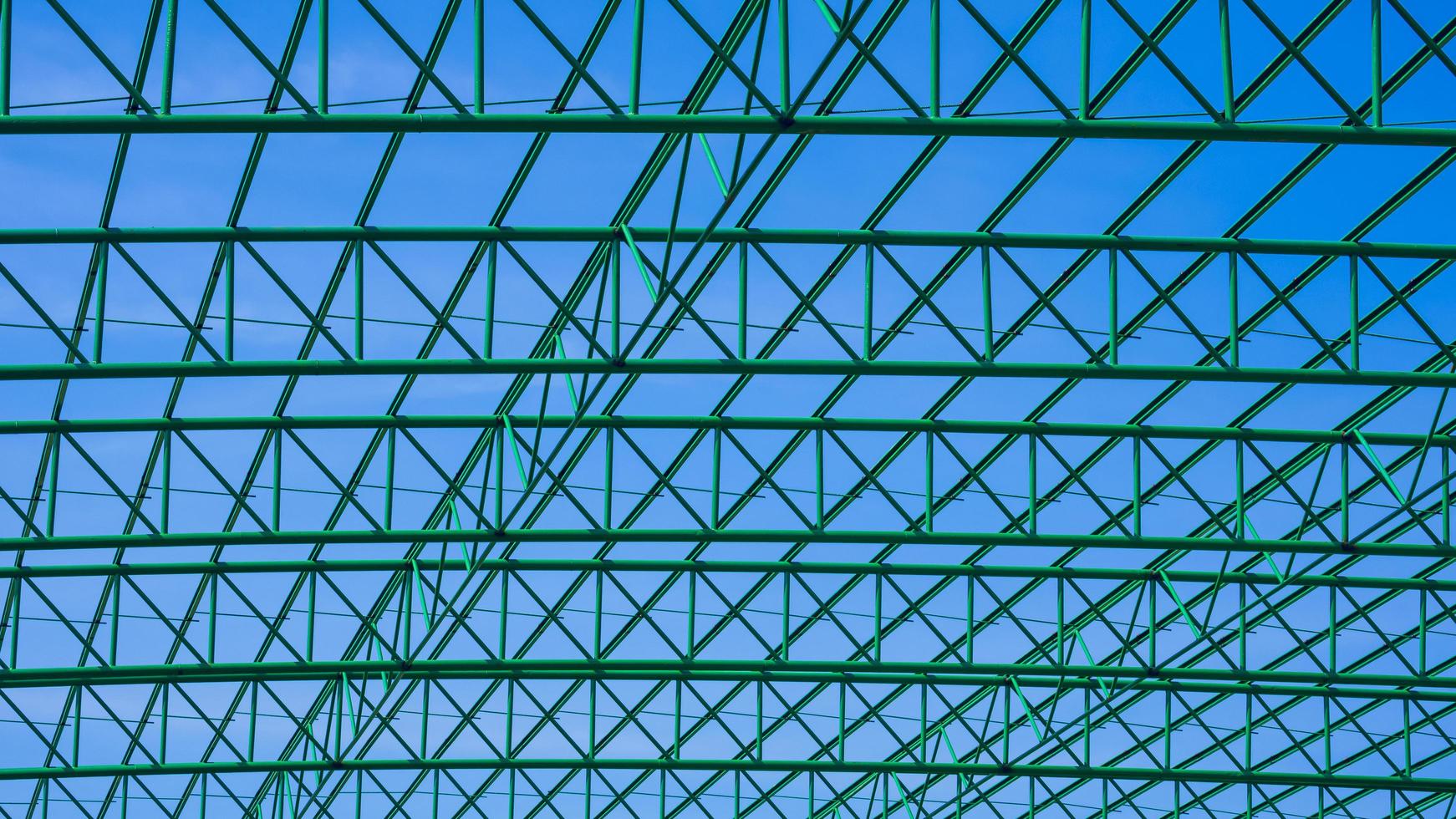 padrão geométrico da estrutura do telhado de metal verde do edifício industrial contra o fundo do céu azul foto