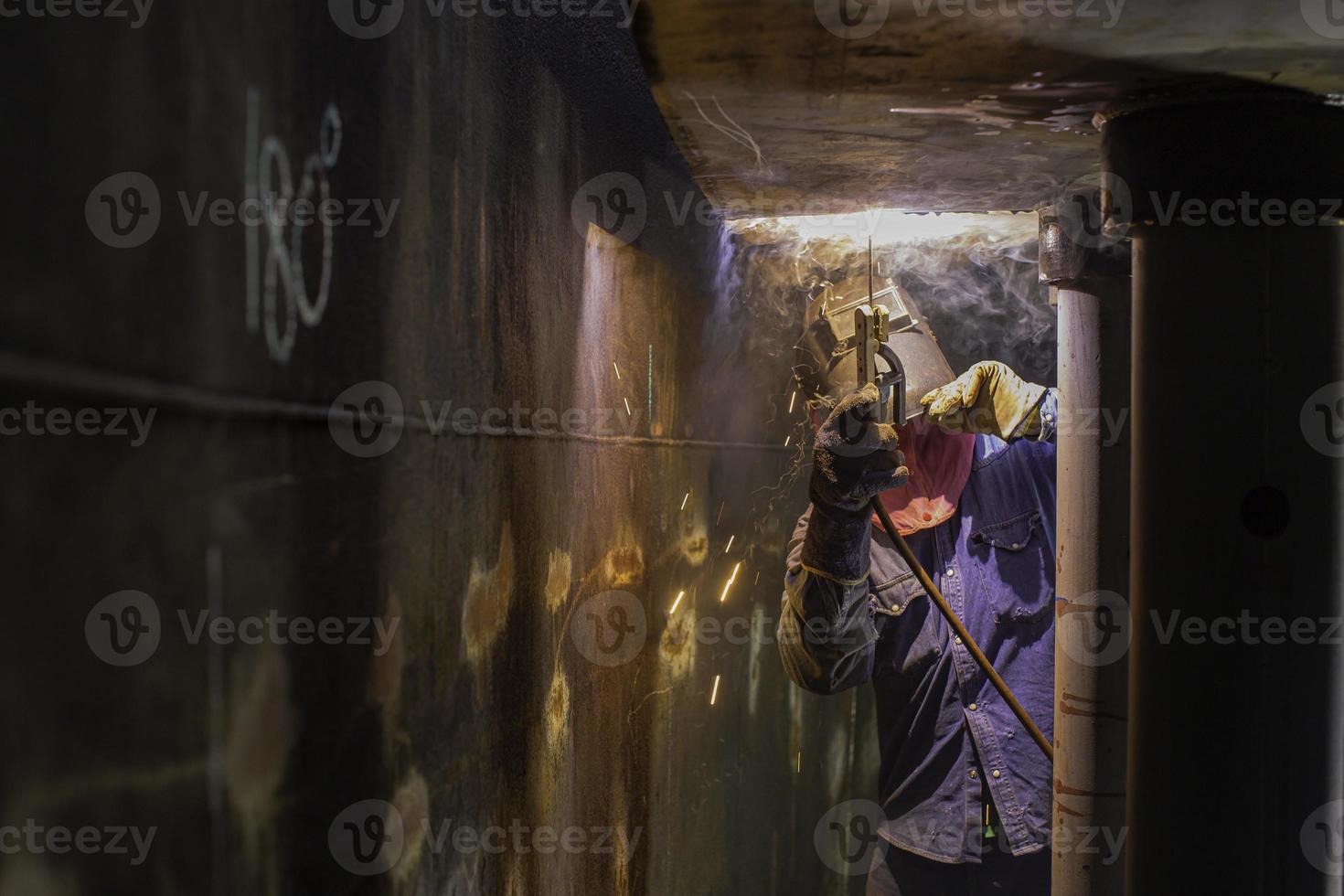 soldar o arco de metal do trabalhador masculino faz parte do óleo do tanque de construção do bico do tanque de máquinas dentro de espaços confinados. foto