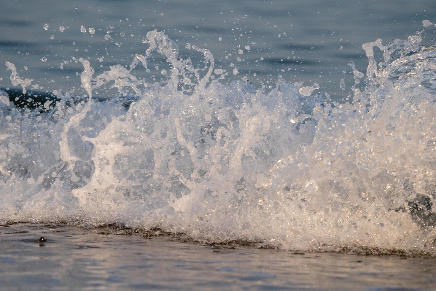 ondas quebrando na maré baixa com espuma do mar foto