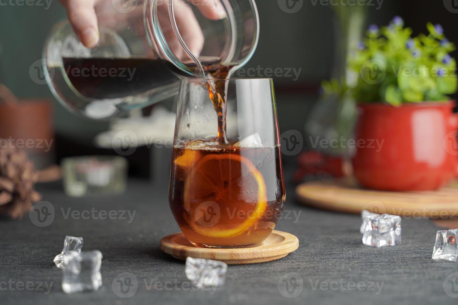 copo de café expresso com suco de limão e limão fatiado fresco na mesa de madeira e espaço de cópia, coquetel de verão, café frio ou chá preto, derramando bebida gelada. foto