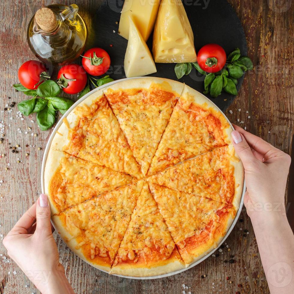 mãos de mulher leva pizza em um prato, vista superior foto