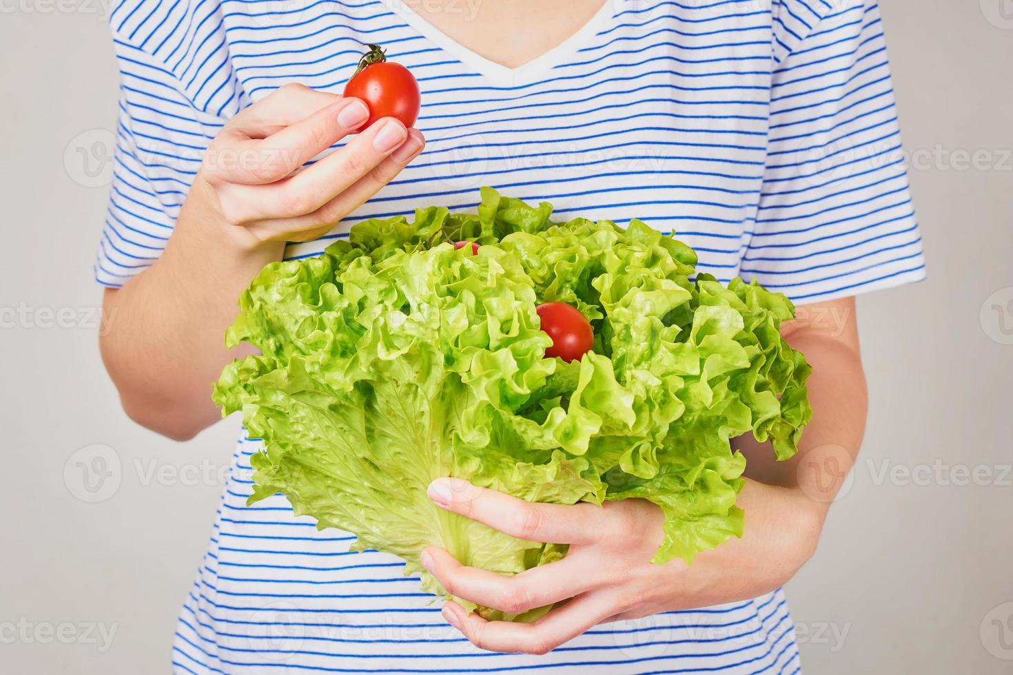 mulher segura buquê de alface com tomate cereja nas mãos. conceito de nutrição saudável foto