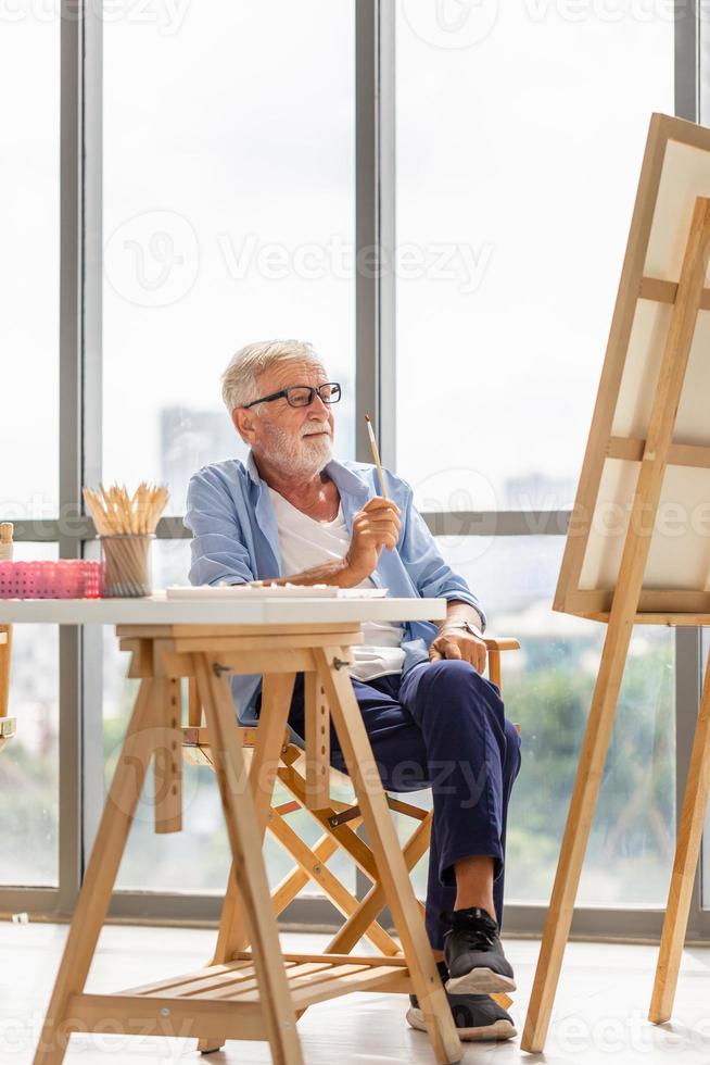 homem idoso pintando em uma tela, sorrindo homem maduro pintando em tela em casa, conceitos de aposentadoria feliz foto