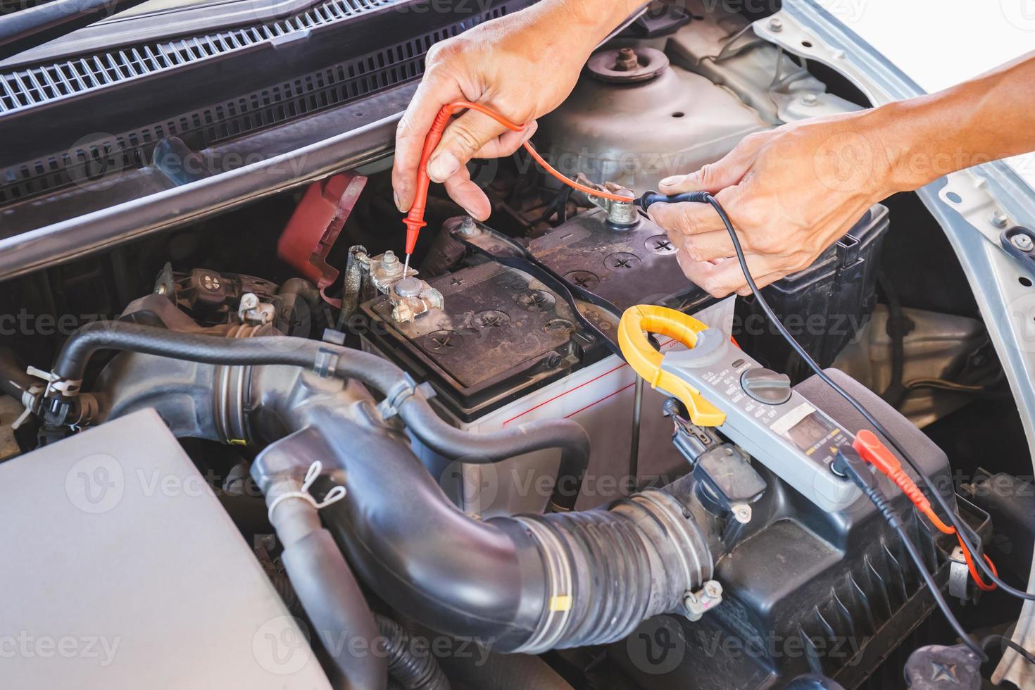 mecânico de automóveis trabalhando no motor do carro, verificando a bateria na garagem mecânica, serviço de reparo e manutenção foto