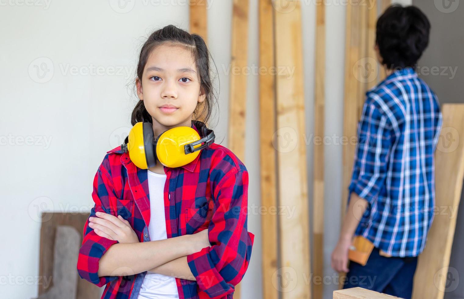 menina de pé com os braços cruzados olhando para a câmera turva menino adolescente em uma oficina de carpintaria. equipe infantil na oficina do artesão foto