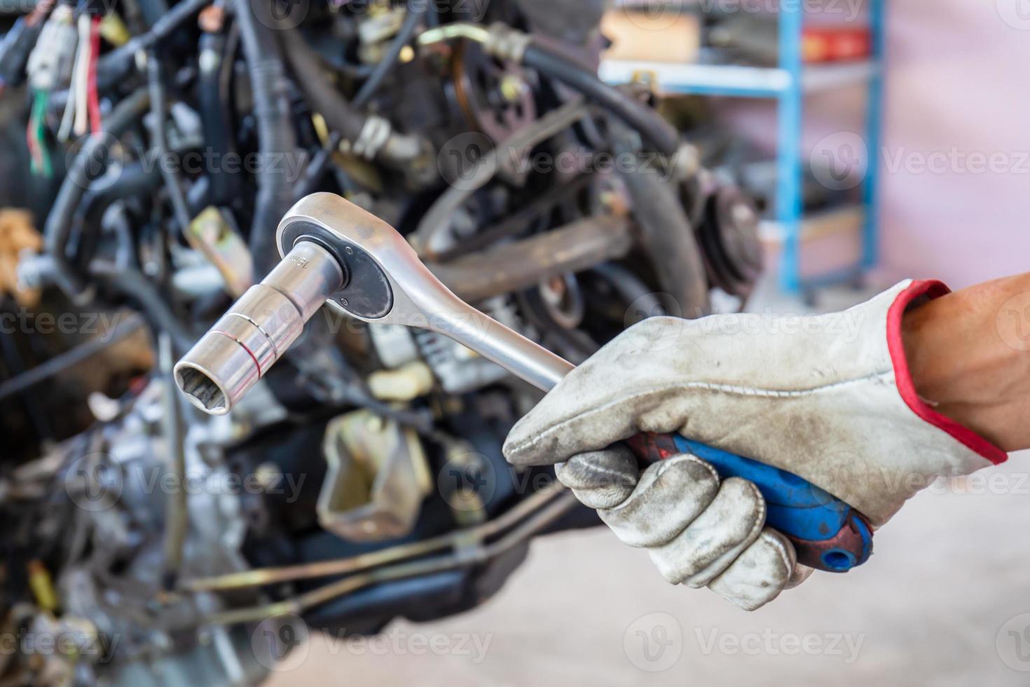 mão do mecânico de automóveis segurando a chave de soquete, serviço de reparo automotivo na oficina foto