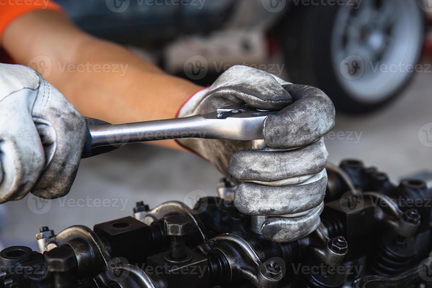 mão de mecânico de automóveis ajustando um motor com chave de soquete, serviço de reparo automotivo na oficina foto