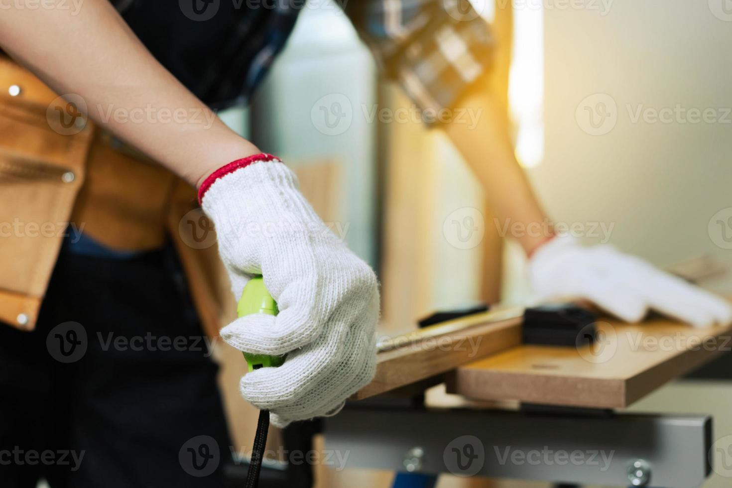 carpinteiro segurando uma fita métrica na bancada de trabalho. artesão em uma oficina de carpintaria foto