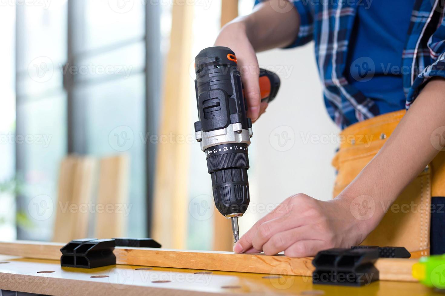 montar móveis. homem segurando a furadeira elétrica de montagem de móveis, artesão com furadeira na chave de fenda elétrica foto