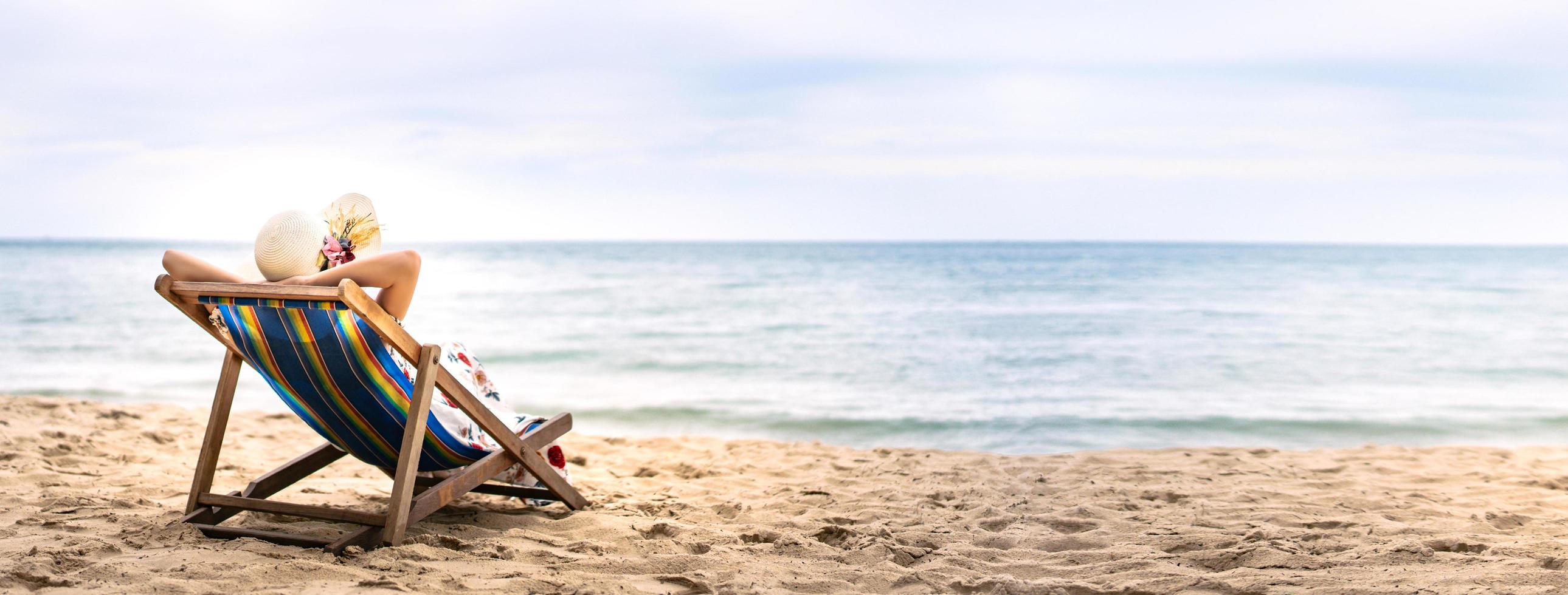 jovem mulher asiática relaxante na cadeira de praia com espaço de cópia foto