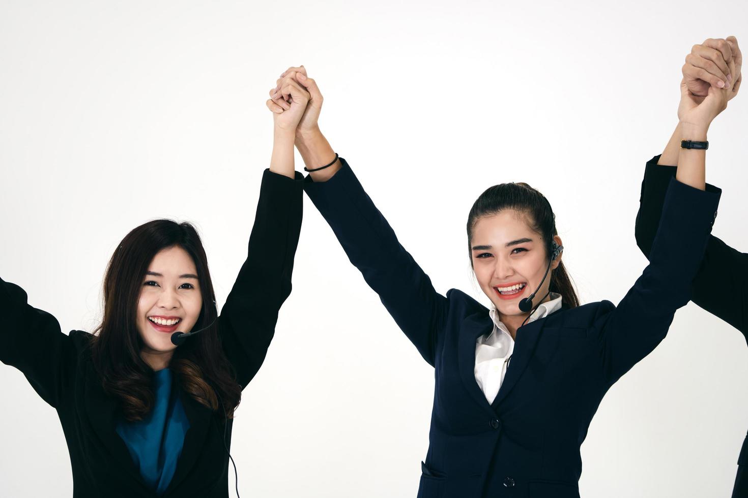 mulher de equipe de funcionários de negócios asiáticos usa fone de ouvido e esticando o braço com cara de feliz. foto