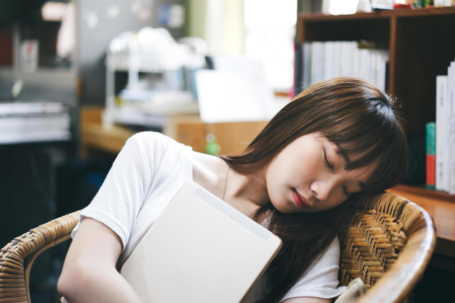 Descanse a mulher adolescente asiática cansada e segure o tablet relaxar dormindo. foto