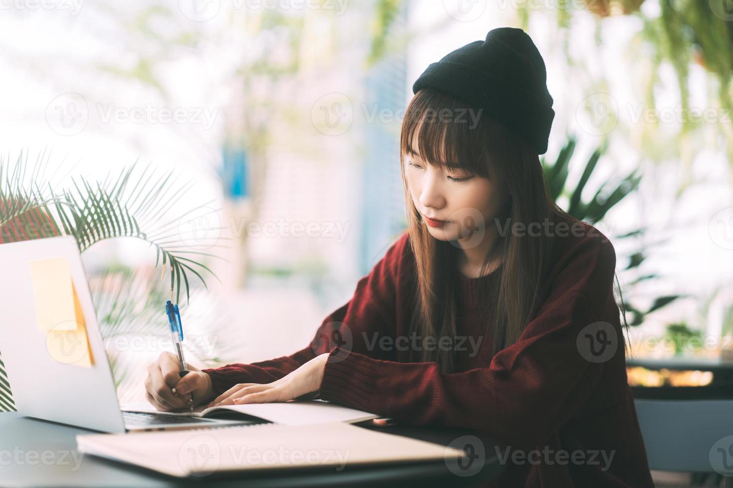 mulher jovem estudante universitário asiático adulto com laptop para estudar no café em dia de inverno. foto