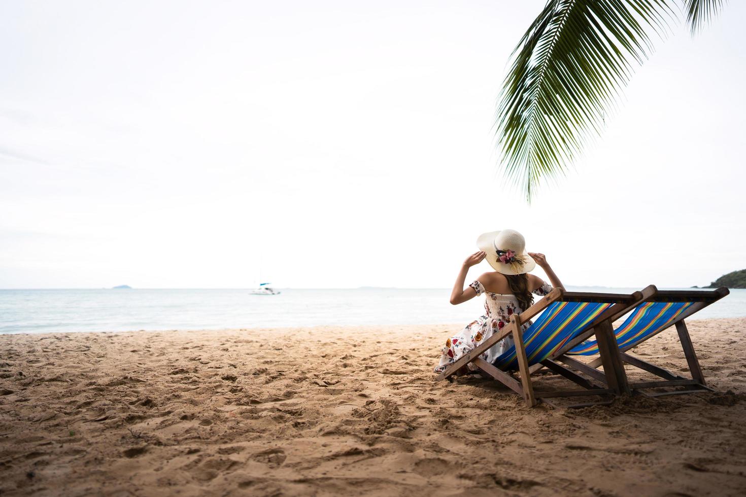 férias de verão na praia segure um chapéu foto