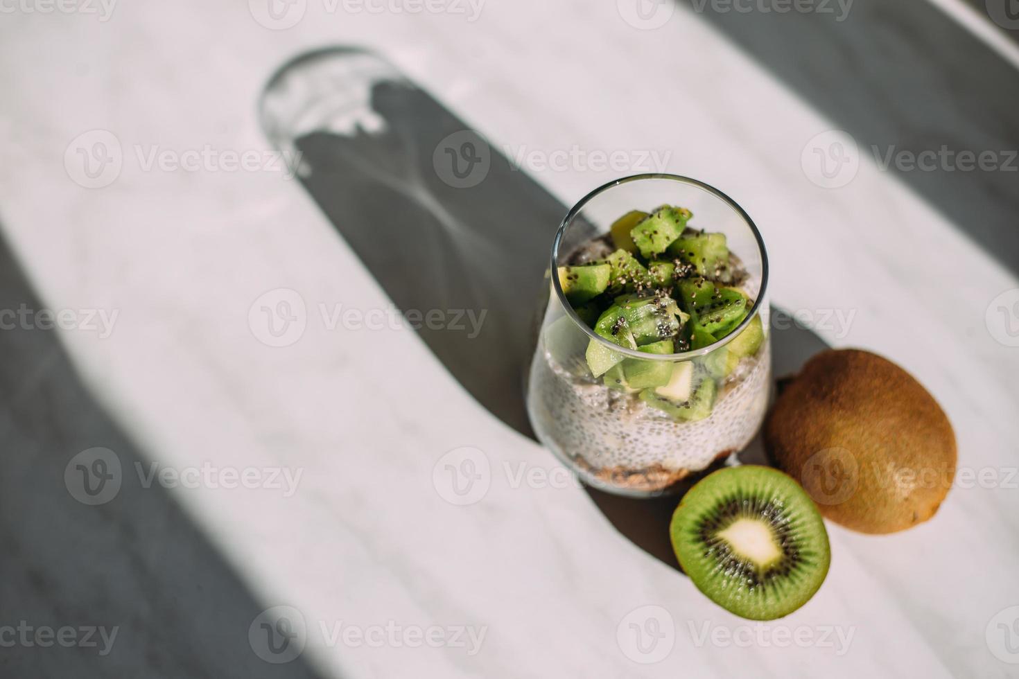 café da manhã saudável. pudim de chia com kiwi e granola em vidro foto