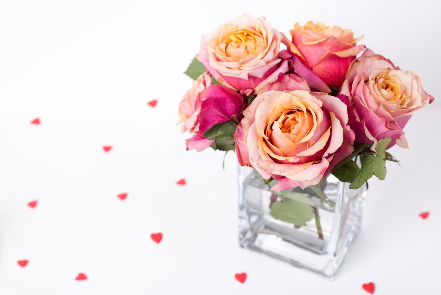 rosas cor de rosa e ornamentos de forma de coração em fundo branco foto