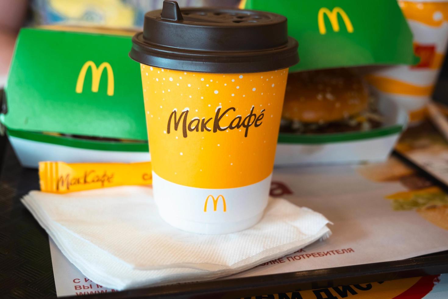 um copo de papel do mcdonald's coffee com a inscrição maccafe em russo e um hambúrguer em uma caixa em uma bandeja. cadeias de restaurantes de fast food. Rússia, Kaluga, 21 de março de 2022. foto