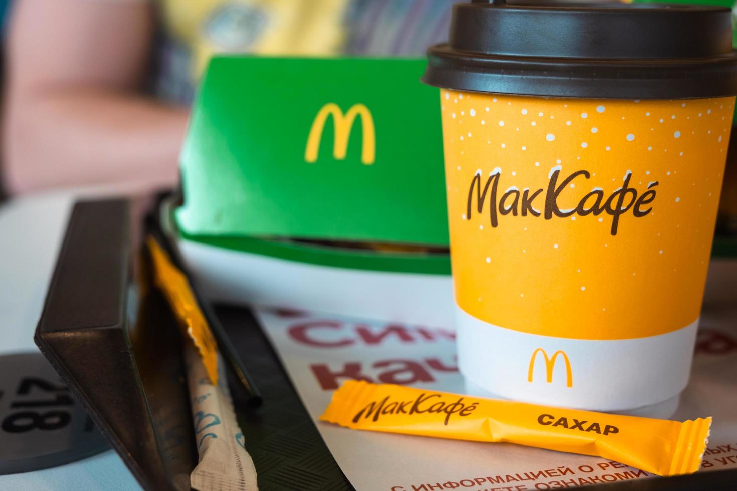 um copo de papel do mcdonald's coffee com a inscrição maccafe em russo e um hambúrguer em uma caixa em uma bandeja. cadeias de restaurantes de fast food. Rússia, Kaluga, 21 de março de 2022. foto