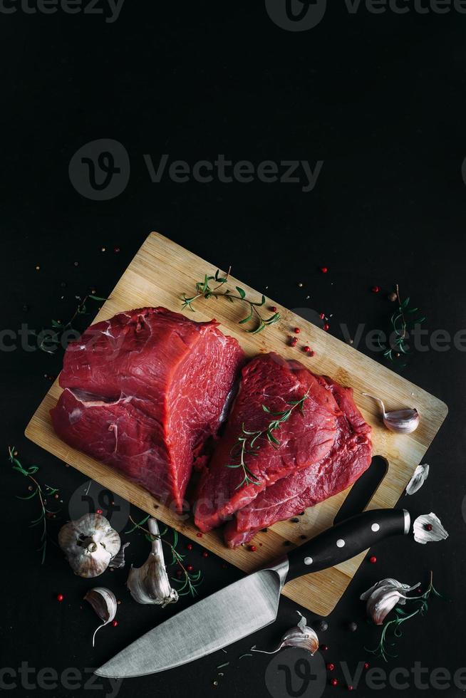 carne fresca e crua. pedaço inteiro de carne vermelha pronto para cozinhar na grelha ou churrasco. quadro-negro de fundo preto. foto