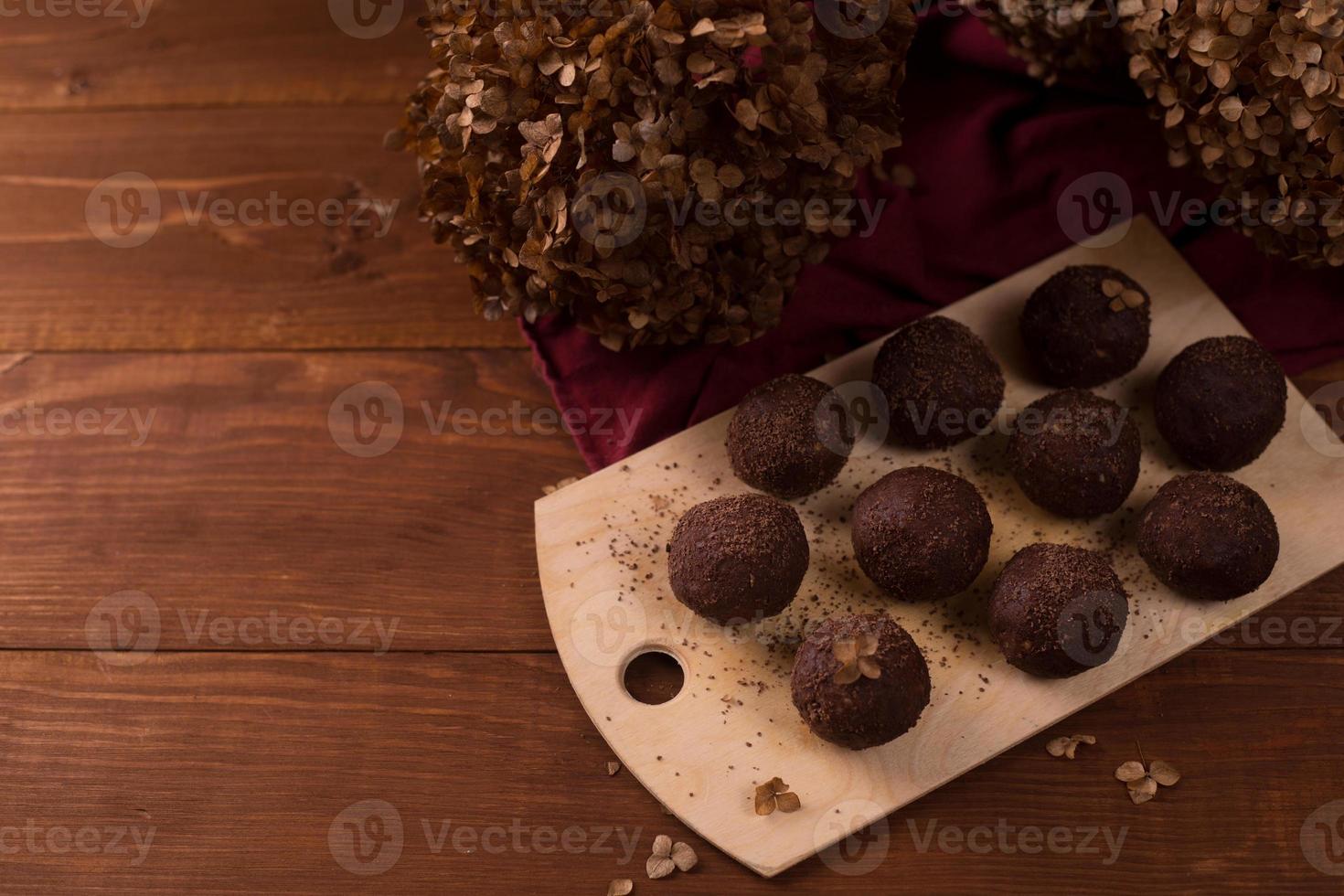 bolas de cacau, bolos de trufas de chocolate a bordo em fundo de madeira foto