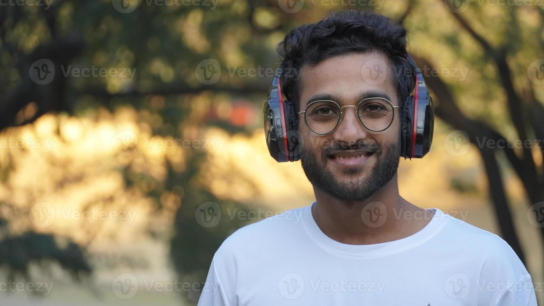 homem com fone de ouvido, homem indiano bonito com fone de ouvido com fundo bonito foto