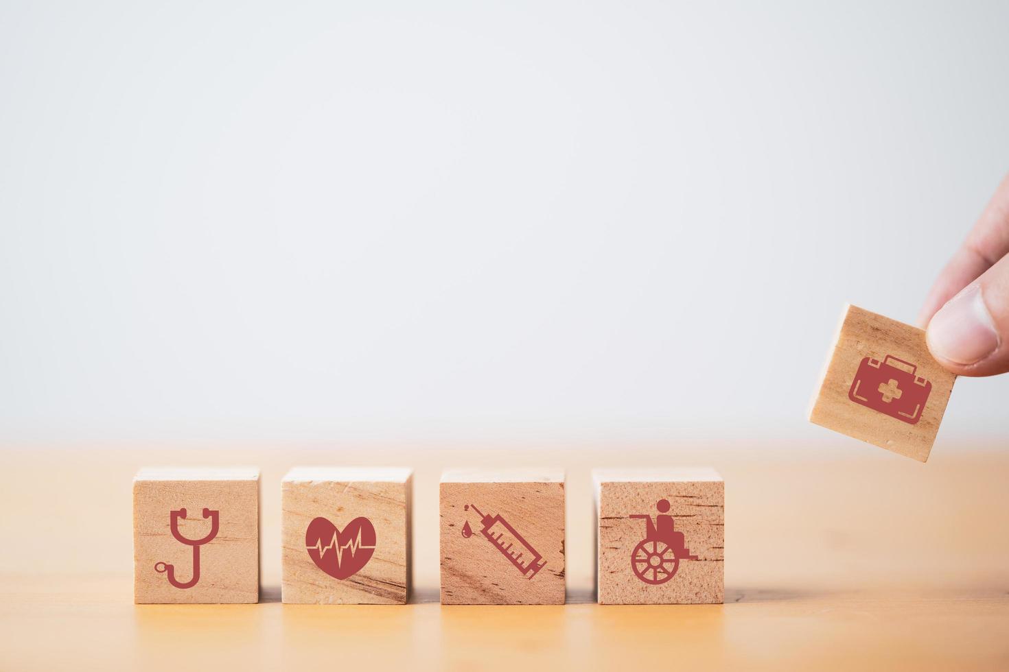 mão colocando e empilhando cubo de bloco de madeira que imprime cuidados de saúde de tela e ícones médicos para o conceito de saúde e bem-estar. foto