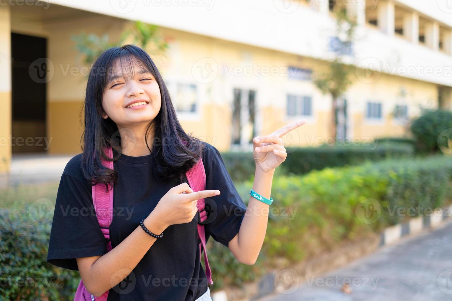 jovem estudante segura livro rosa e mochila na escola, de volta à escola. foto