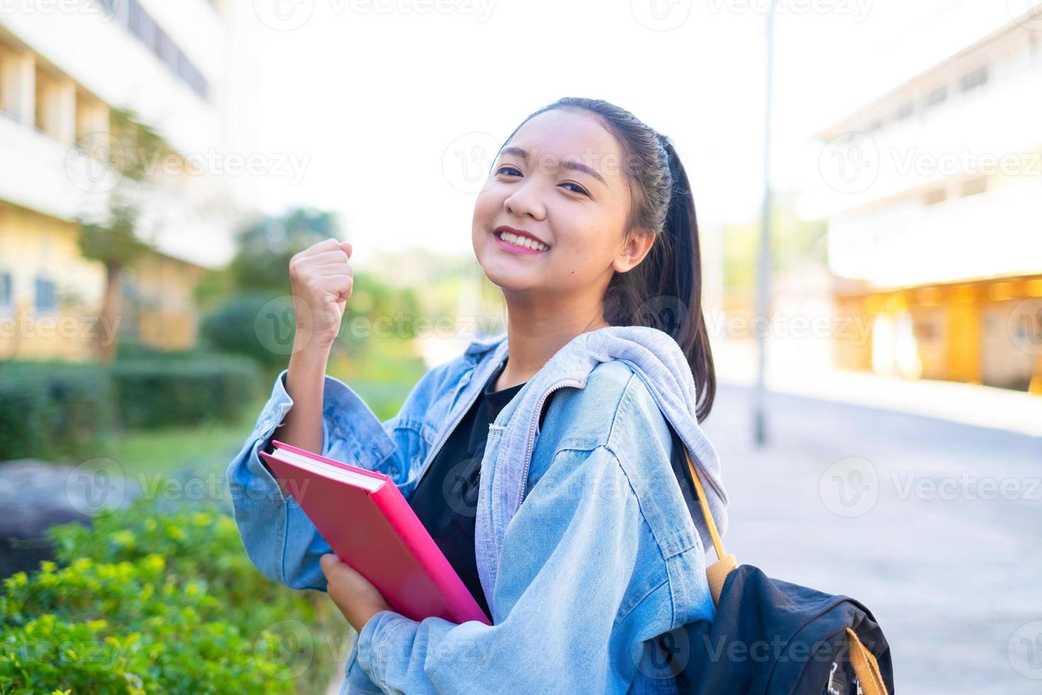 aluna feliz segura livro e mochila na escola, menina asiática. foto