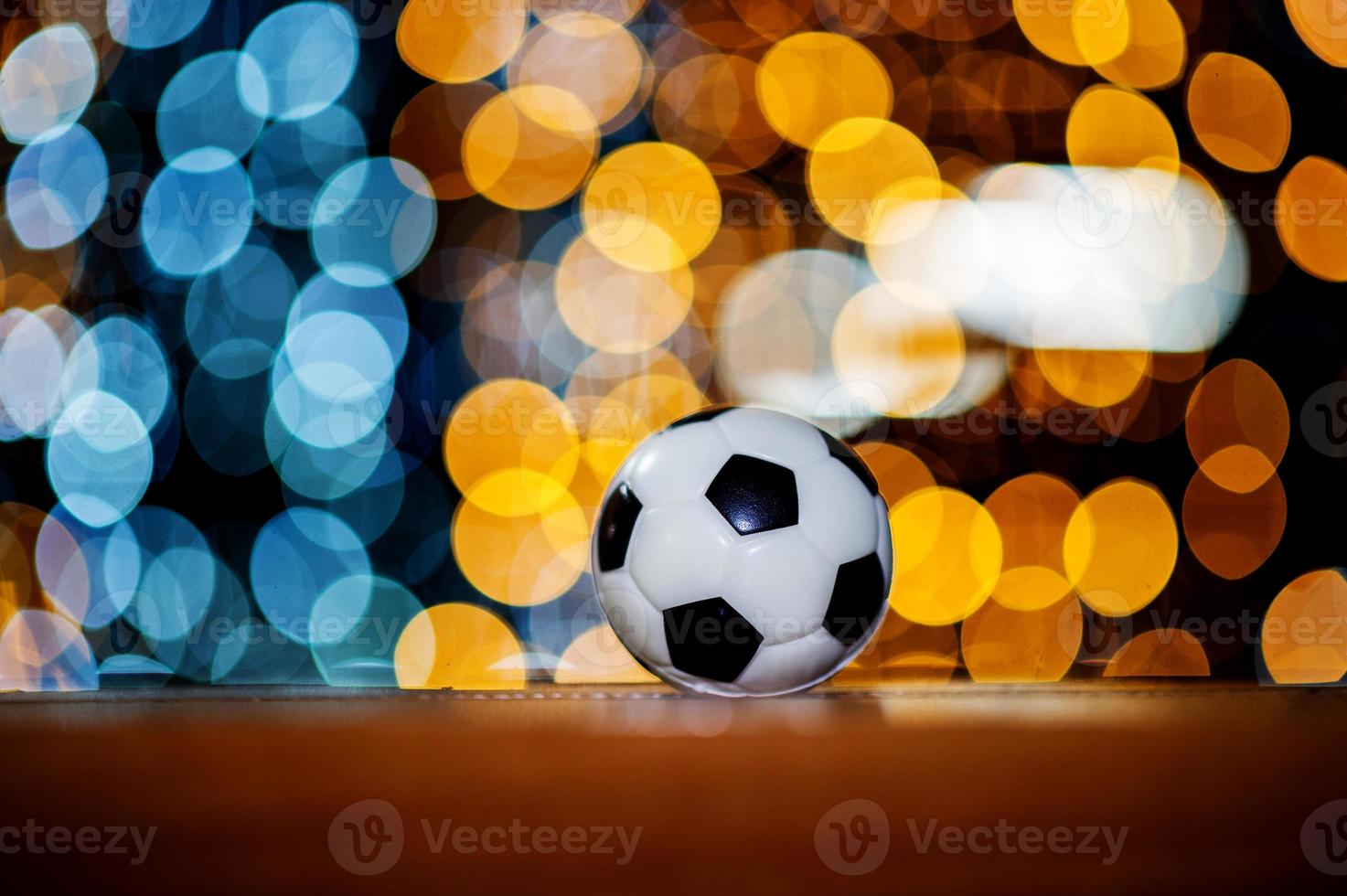 a bola de futebol branca é colocada em um pedaço de madeira e tem um belo bokeh de fundo. foto