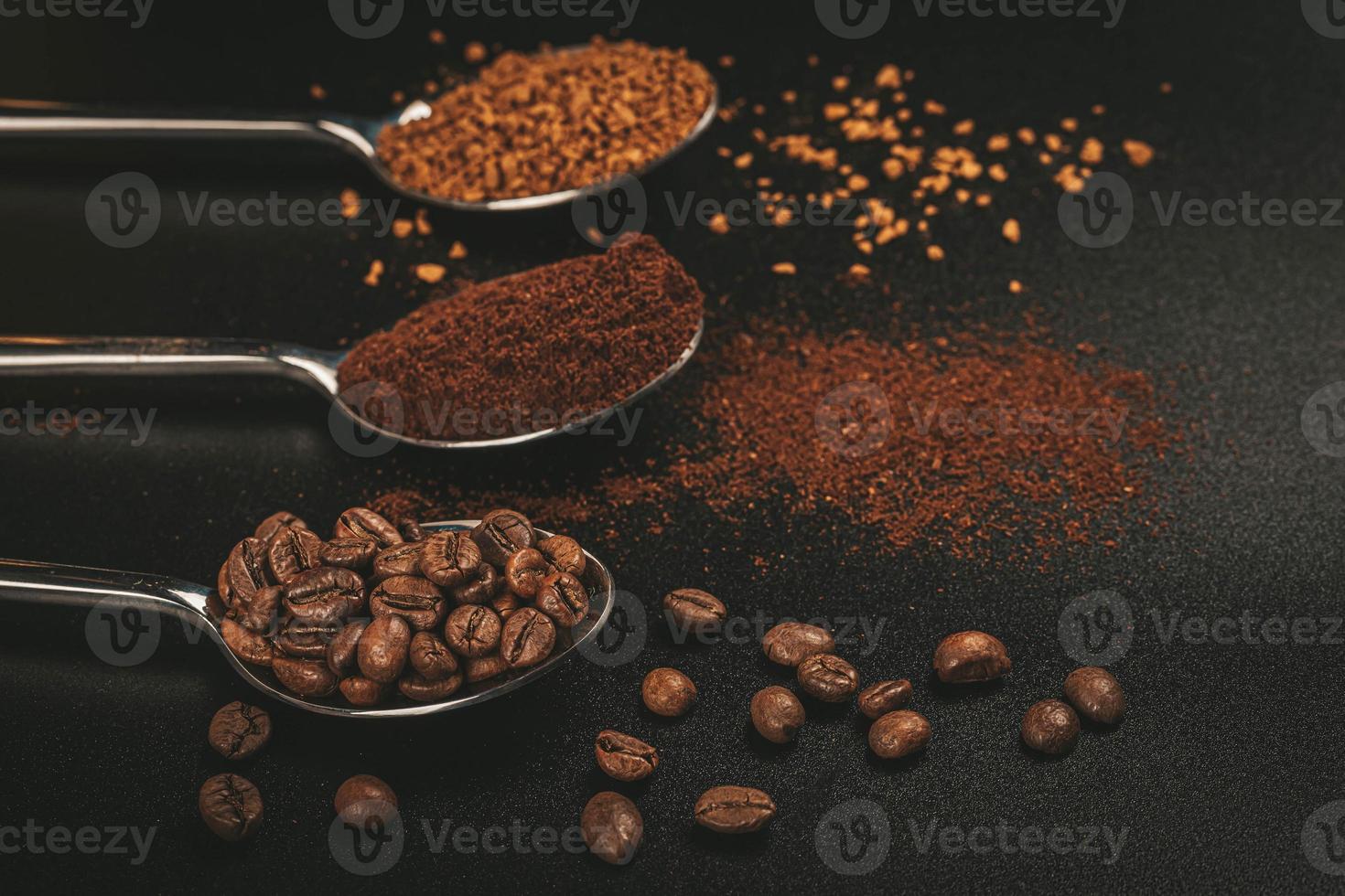 três colheres de café com café solúvel, grãos de café e café moído em fundo escuro foto