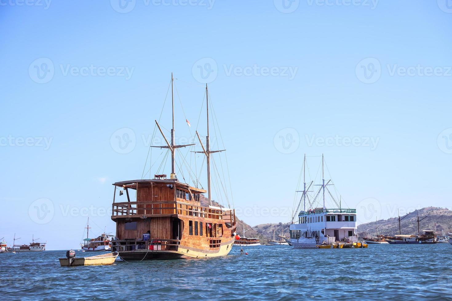 vários barcos de madeira tradicionais flutuando no mar perto de uma ilha em labuan bajo foto