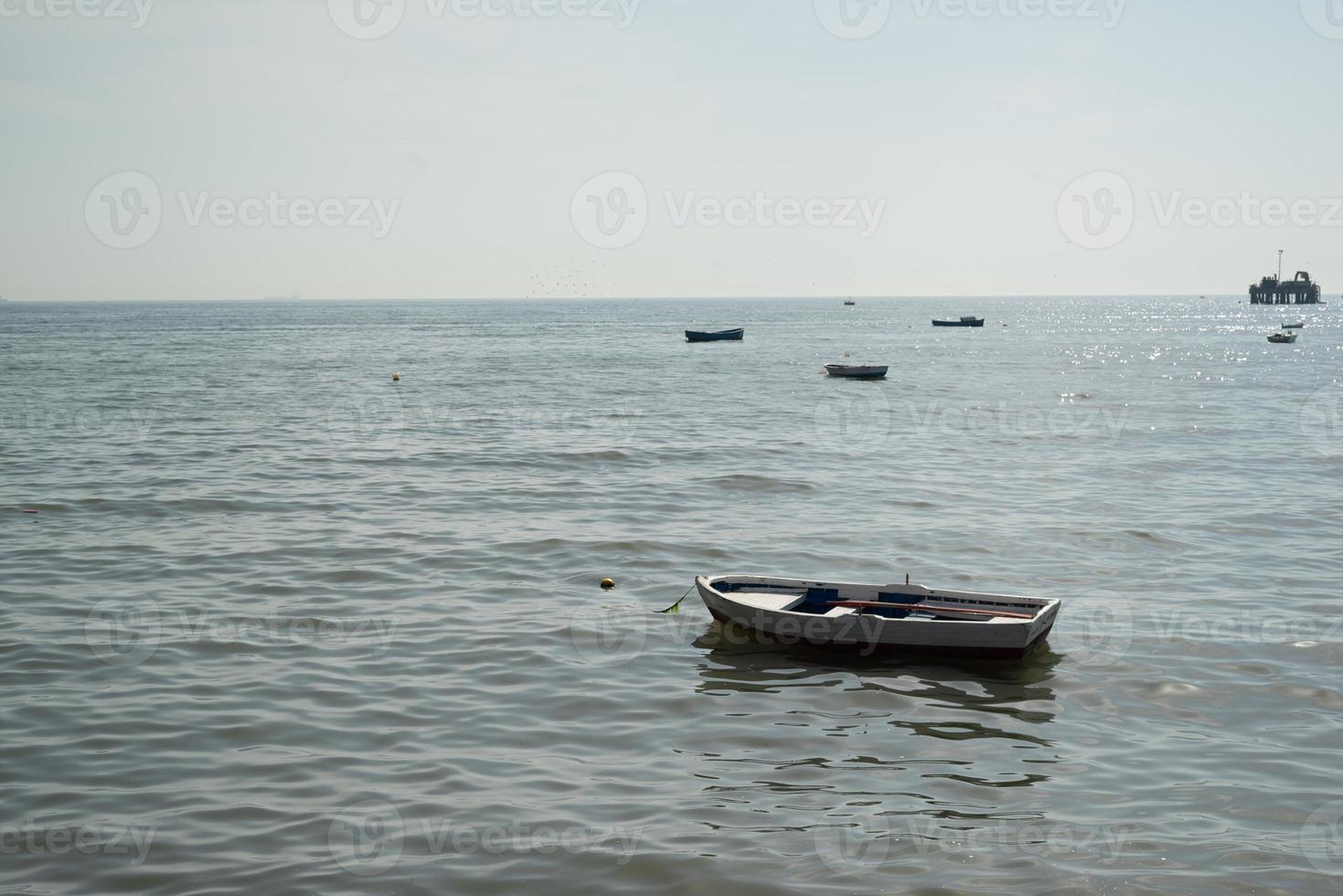 único barco com vista mar e praia com outros barcos no fundo foto