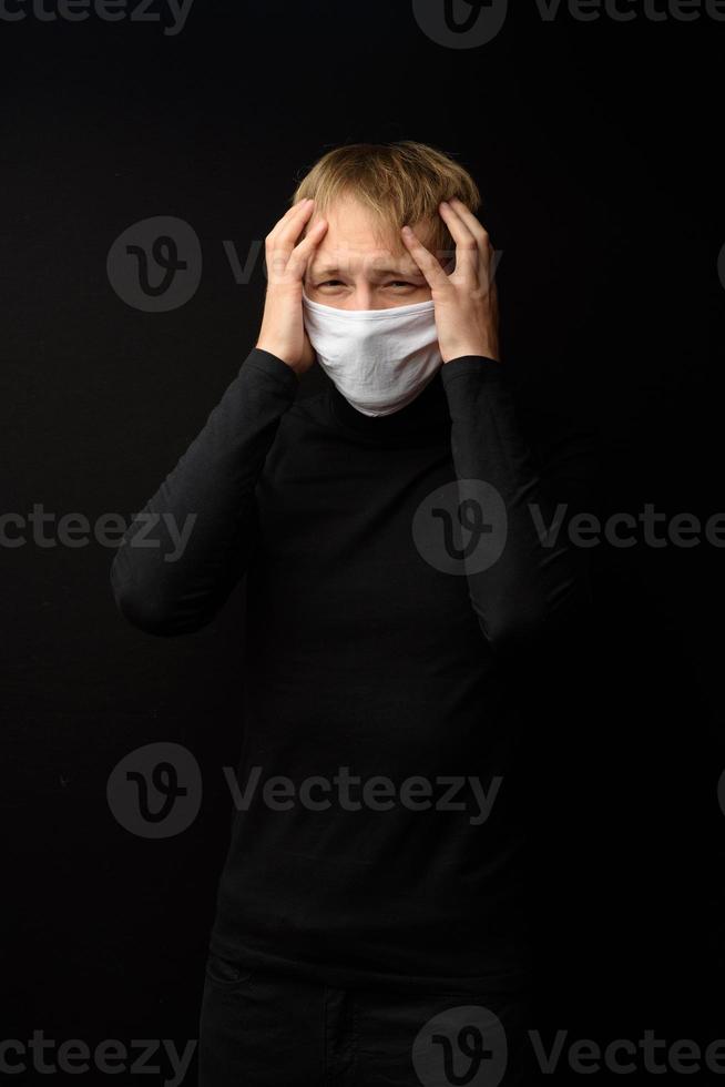 homem de meia idade com retrato de máscara facial médica de perto ilustra a doença de coronavírus pandêmico em fundo escuro. conceito de contaminação de surto covid-19. foto
