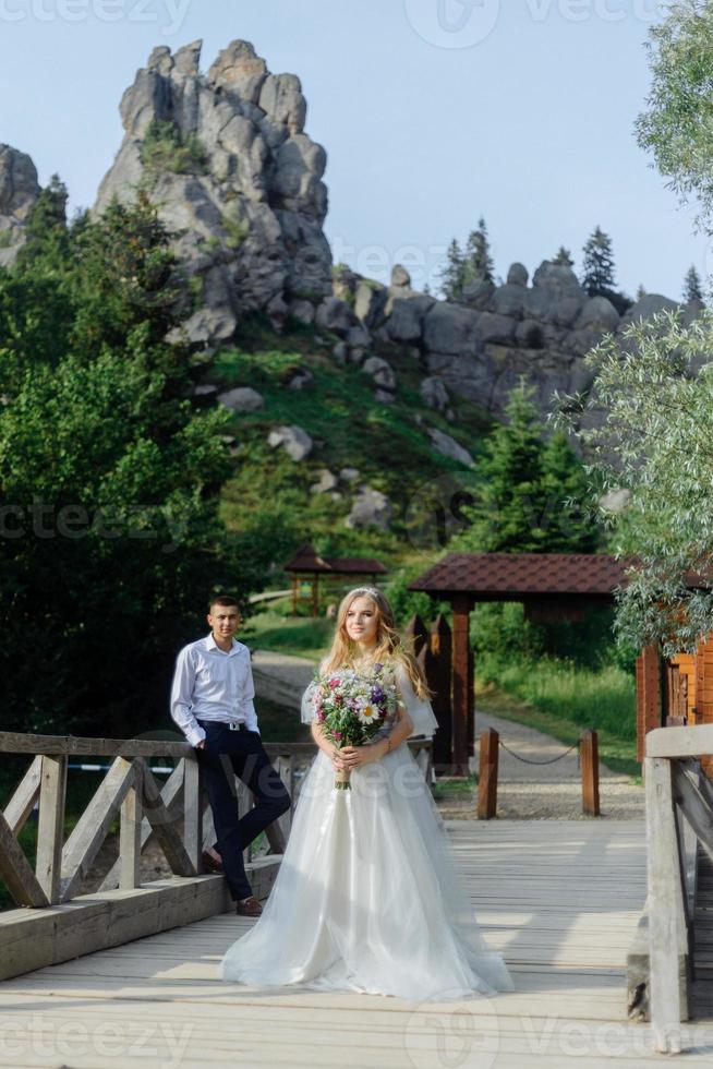 ensaio fotográfico de um casal apaixonado nas montanhas. a garota está vestida como uma noiva em um vestido de noiva. foto