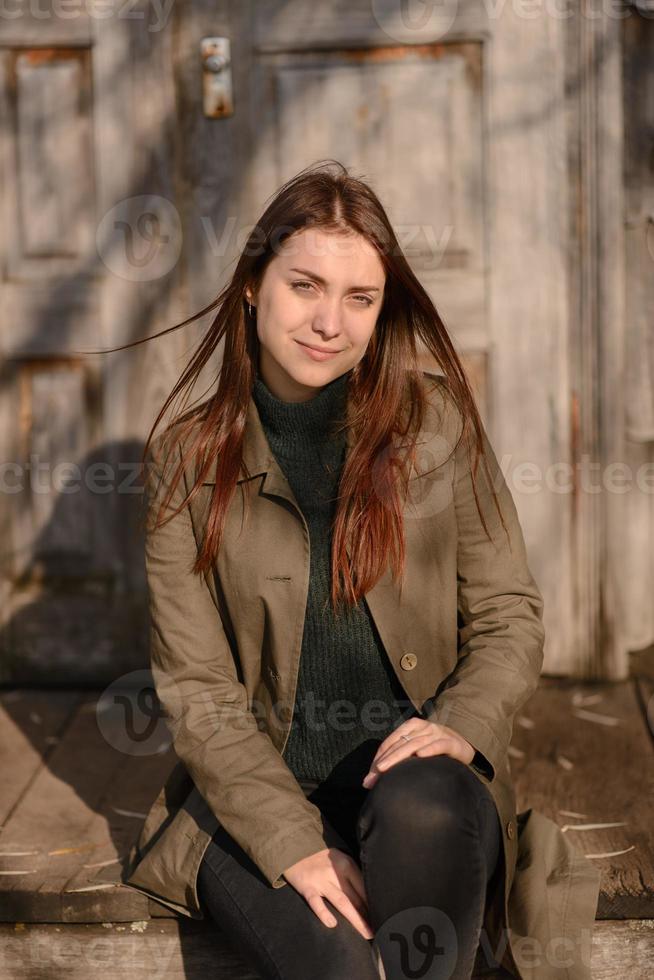 uma jovem senta-se nos degraus da entrada de uma casa de madeira. foto