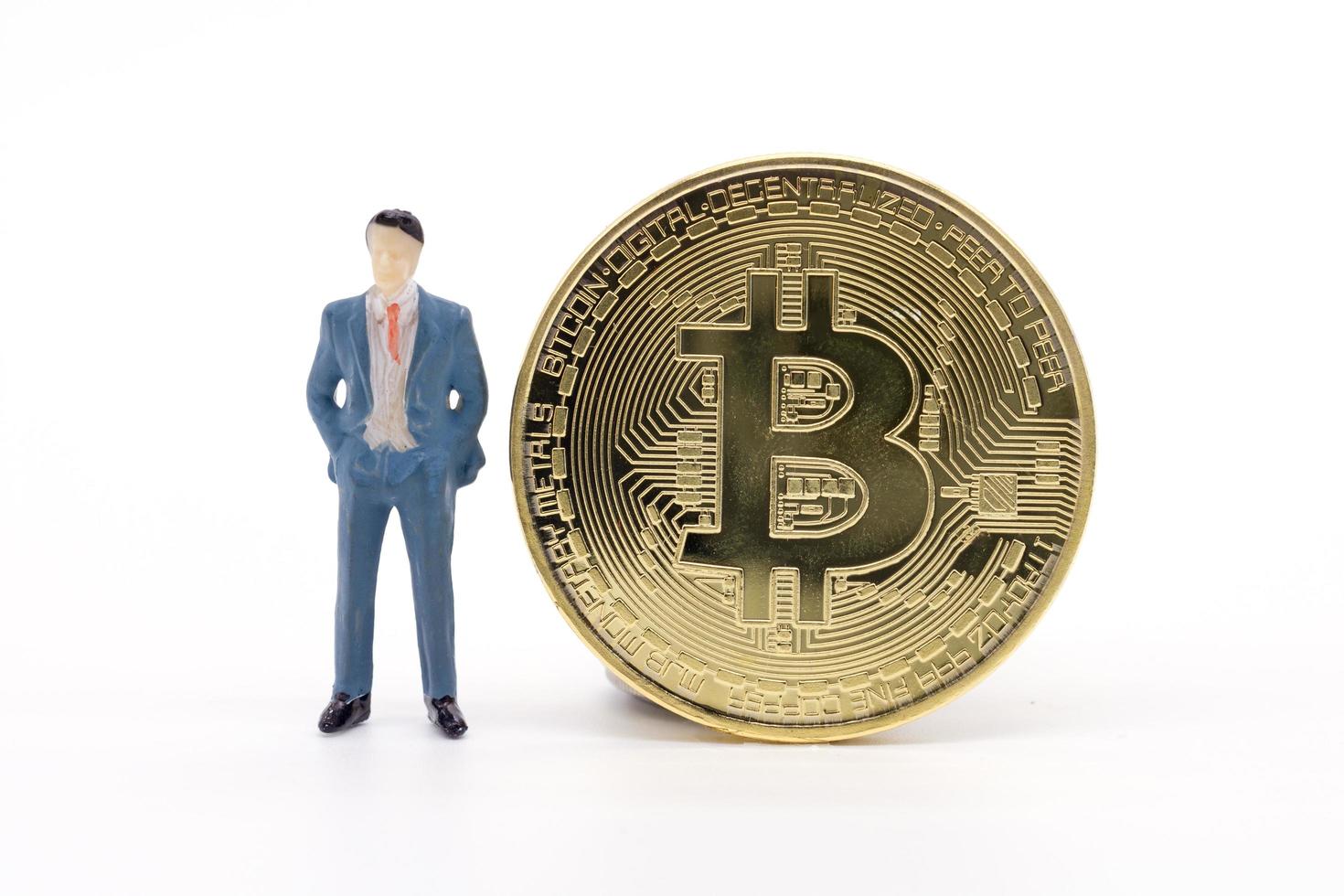 empresário em miniatura e bitcoin em fundo branco foto