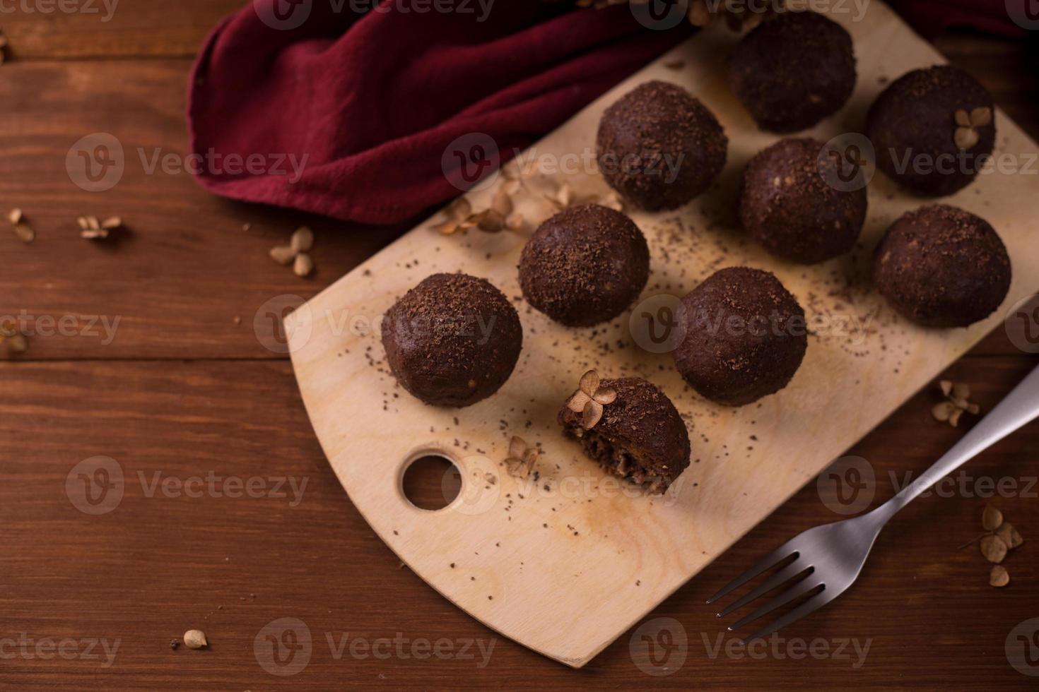 bolas de cacau, bolos de trufas de chocolate a bordo em fundo de madeira foto
